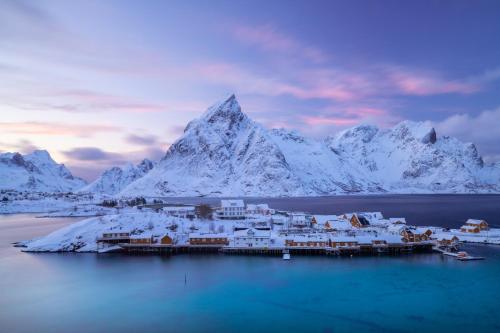 a town in the middle of the water with snow covered mountains at Sakrisøy Rorbuer in Reine