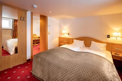 a hotel room with a large bed and a mirror at Hotel Tannbergerhof im Zentrum von Lech in Lech am Arlberg