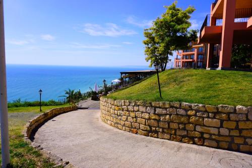 a stone wall next to a building next to the ocean at Ваканционни Апартаменти Калиакрия - Holiday Apartments Kaliakria in Topola