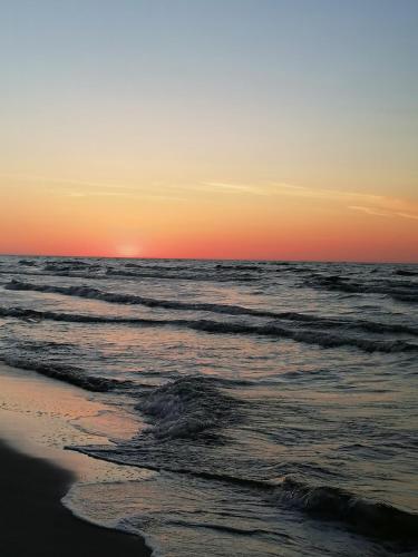 a sunset on the beach with the ocean at Apartament przy Brzozowej Polanie in Perlino