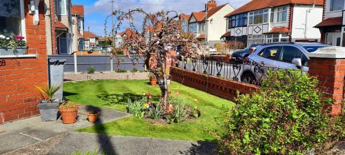 un pequeño jardín con un pequeño árbol en un patio en Cosy and stylish house on the coast near Liverpool, en Wirral