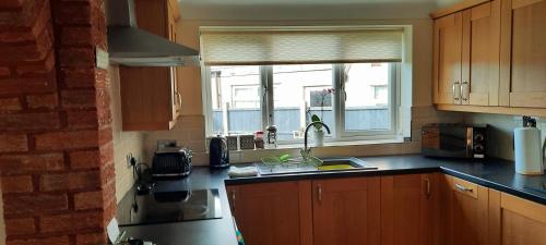 a kitchen with a sink and a window at Cosy and stylish house on the coast near Liverpool in Wirral