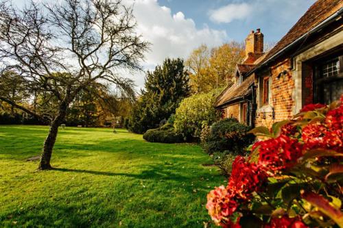 a house with red flowers in front of a yard at Breathtaking Elizabethan Manor House in Burnham on Crouch