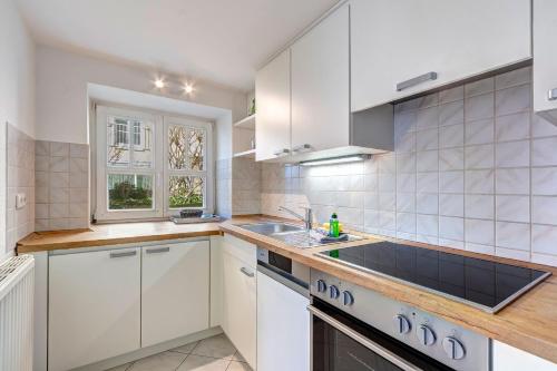 a kitchen with white cabinets and a sink and a window at Haus Seeblick Hotel Garni & Ferienwohnungen in Zinnowitz
