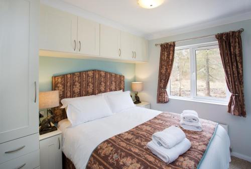 1 dormitorio con 1 cama con toallas en 2-Bed Cottage with Hot Tub at Loch Achilty NC500, en Strathpeffer