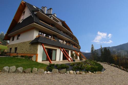 a house on a hill with rocks in front of it at ZAKOkryjówka Butorowy Residence in Kościelisko