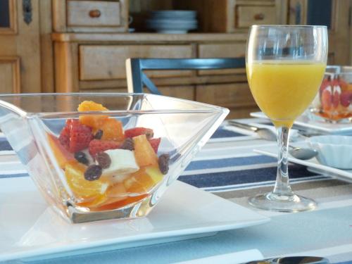 a bowl of fruit next to a glass of orange juice at LE CHALET de LA LONGERE in Beuvry-Nord