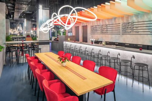 a restaurant with a wooden table and red chairs at Vienna House by Wyndham Andel's Prague in Prague