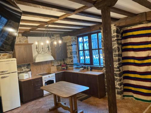 a kitchen with wooden cabinets and a table in it at Къща Александрова с басейн вътрешен и отопляем in Arda