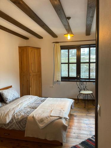 a bedroom with a bed and a table and windows at Къща Александрова с басейн вътрешен и отопляем in Arda