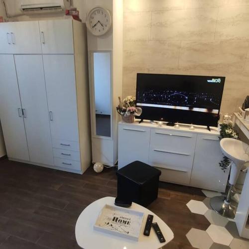 a living room with a tv and white cabinets and a table at Zone Vidikovac in Belgrade