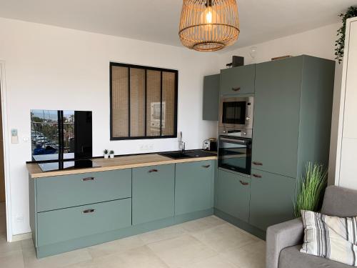 une cuisine avec des placards bleus et une fenêtre dans l'établissement VUE SUR LES ILES D'OR, à Hyères