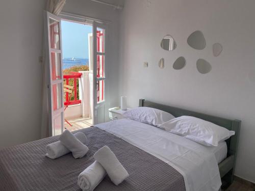 a bedroom with a bed with white pillows and a window at Elenitas Town house with Balcony and Sea View in Mýkonos City