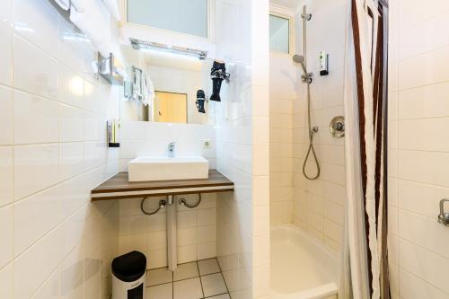 a white bathroom with a sink and a shower at Turmhotel Rhein-Main in Dreieich