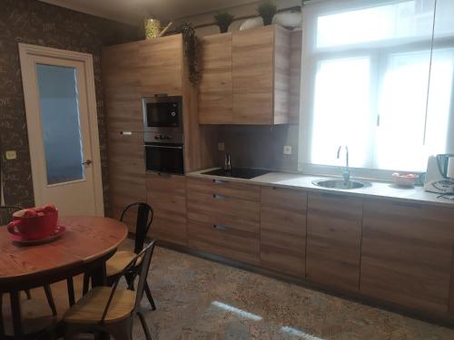 cocina con armarios de madera, mesa y ventana en bilbao center apt 90´s PARKING, en Bilbao