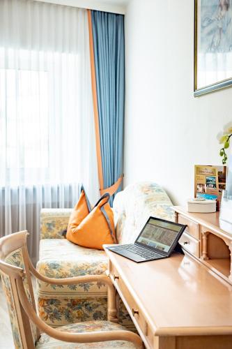 a room with a desk with a laptop on a couch at Hotel-Restaurant Minichmayr in Steyr