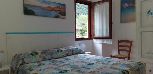 a bedroom with a bed and a chair and a window at Casa Lucia Campagna Relax in Dorgali