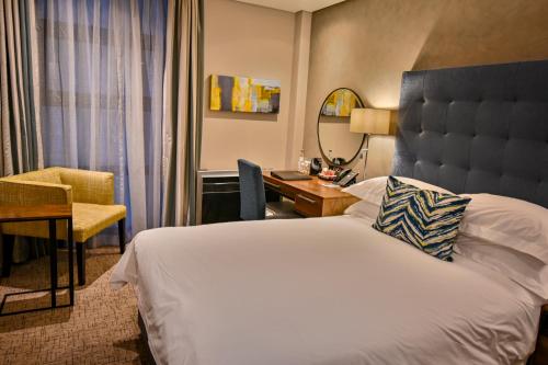 a hotel room with a large bed and a desk at Premier Splendid Inn Bloemfontein in Bloemfontein