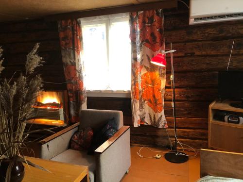 sala de estar con chimenea, silla y ventana en Vedru Puhketalu, en Väike-Rakke