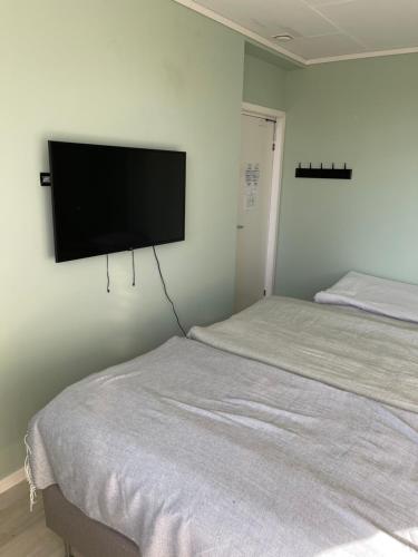 a bedroom with a bed and a flat screen tv on the wall at Bergkvara Vandrarhem in Bergkvara