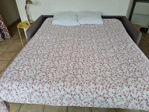 - un lit avec une couverture fleurie dans l'établissement Studio 261 escale plage résidence, au Grau-du-Roi