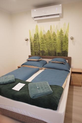 2 posti letto in una camera con una foto di alberi di Csengő Vendégház a Kiskőrös