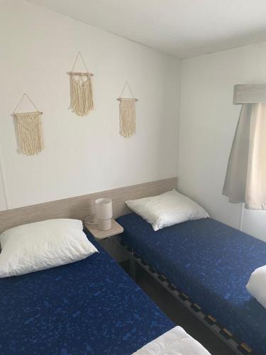 two beds in a room with blue sheets and white pillows at Zee&Zout, chalet 6 pers. bij Renesse en strand! in Renesse