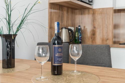 a bottle of wine sitting on a table with two wine glasses at BURSZTYNOVA Apartamenty Piamola in Kąty Rybackie