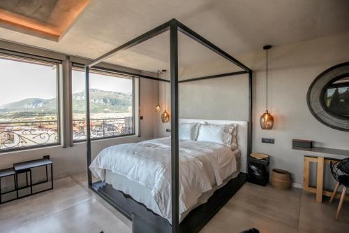 a bedroom with a canopy bed and a large window at Meteora Heaven and Earth premium suites - Adults Friendly in Kalabaka