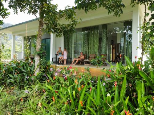 a group of people sitting on the porch of a house at Evergreen Villa - Sinharaja in Deniyaya