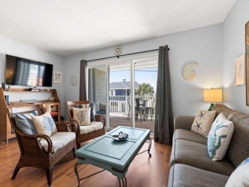 a living room with a couch and chairs and a table at Laid Back By The Sea - Steps from the beach with amazing ocean views, Parking for 2 included, condo in Carolina Beach