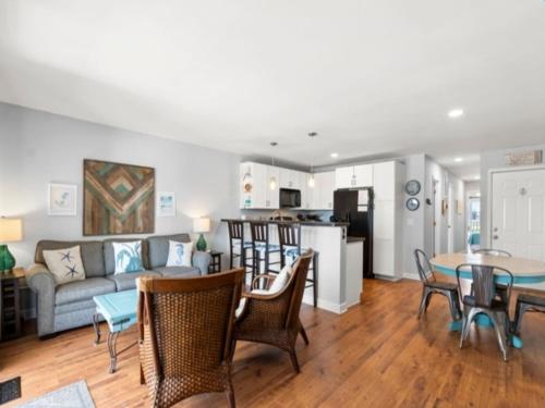 a living room with a couch and a table and chairs at Laid Back By The Sea - Steps from the beach with amazing ocean views, Parking for 2 included, condo in Carolina Beach