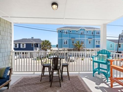 a patio with chairs and a table and a blue building at Laid Back By The Sea - Steps from the beach with amazing ocean views, Parking for 2 included, condo in Carolina Beach