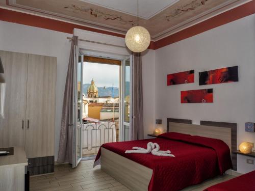 sypialnia z czerwonym łóżkiem i dużym oknem w obiekcie Le Cupole Decò w mieście Palermo