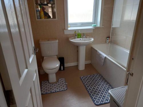 a bathroom with a toilet and a sink and a tub at Inviting light and airy 3-Bed Apartment in Wick in Wick