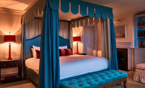 um quarto com uma cama de dossel e cortinas azuis em The Mitre, Hampton Court em Kingston upon Thames
