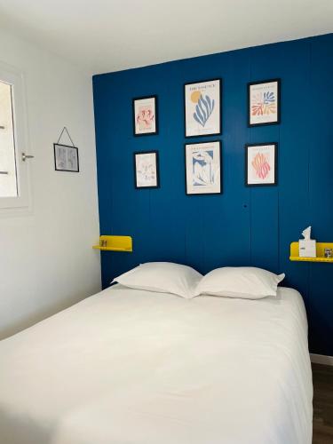 - une chambre avec un mur bleu et un lit blanc dans l'établissement Logis des pêcheurs, à Meschers-sur-Gironde