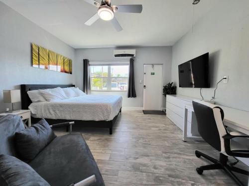 a bedroom with a bed and a couch and a tv at Barefoot mailman motel in Lantana