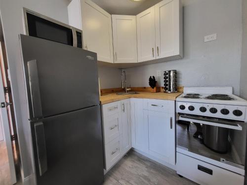 a kitchen with white cabinets and a stainless steel refrigerator at Barefoot mailman motel in Lantana