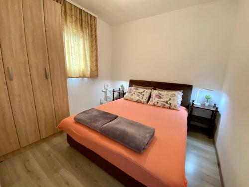 a bedroom with a bed with an orange blanket at Holiday Home Oaza in Čanj