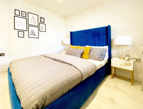 a bed with a blue headboard in a bedroom at MODERN FLAT 10 MINUTES WALK FROM TOWER BRIDGE ! 5 MINUTES from TUBE STATION in London