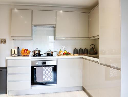 a kitchen with white cabinets and an oven at MODERN FLAT 10 MINUTES WALK FROM TOWER BRIDGE ! 5 MINUTES from TUBE STATION in London