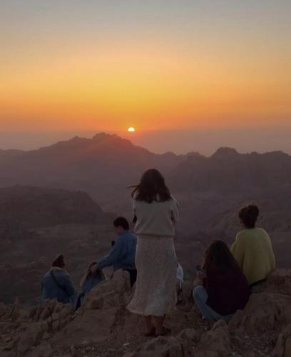 a group of people sitting on a mountain watching the sunset at Petra Desert Dream Hotel in Wadi Musa