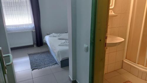 a bedroom with a bed and a bathroom with a sink at Prenoćište Luna 2005 in Novi Sad