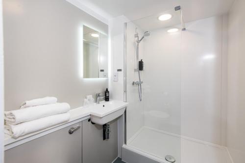een witte badkamer met een douche en een wastafel bij ibis Plymouth in Plymouth