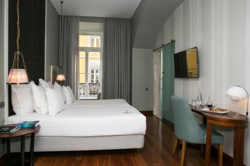 a hotel room with a white bed and a desk at Pousada de Lisboa - Small Luxury Hotels Of The World in Lisbon