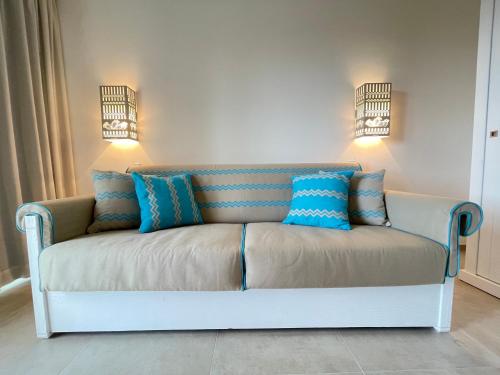 a couch in a room with blue pillows on it at Resort Abbaia Ba in Budoni