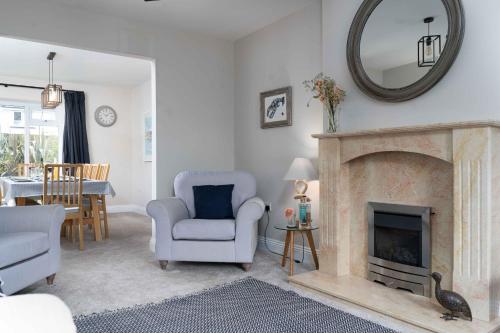 a living room with a fireplace and a chair and a mirror at Merlins in Hayle