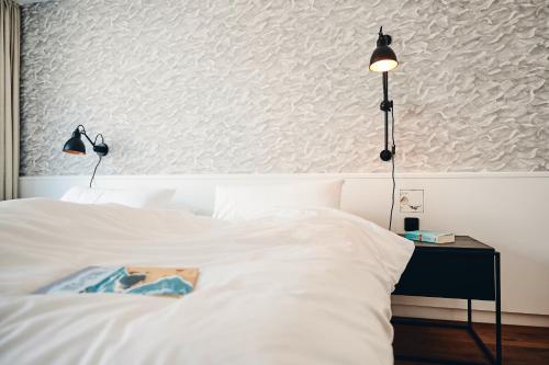 a bedroom with a white bed with two lights on it at Haus am Meer-Ferienwohnungen in Norderney