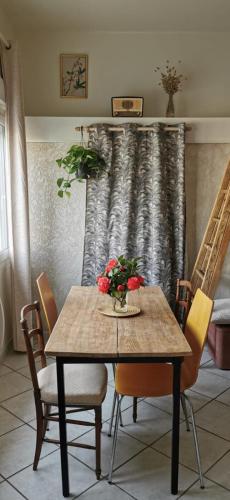 una mesa de comedor con sillas y flores. en Chez Beroy, en Morlaas